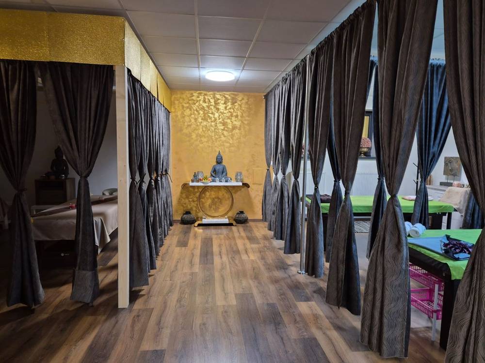 Corridor between massage areas with a golden wall and a Buddha statue