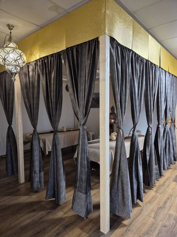 Massage areas separated by curtains under a golden wall